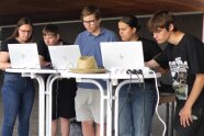 Eine Gruppe von fünf jungen Leuten schaut gebannt auf drei Laptops. Sie übertragen die vorher mit einem Messgerät ermittelten Flur- beziehungsweise Grundstücksdaten in ein Geoinformationssystem.