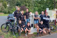 Eine Frau und acht Männer im Radfahrer-Outfit umringen die neue Fahrradreparaturstation in Heimbuchenthal.