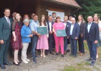 Männer und Frauen haben sich vor einer Hütte im Weinberg aufgereiht. In der Mitte Bayerns Umweltminister Thorsten Glauber. Er ehrte die Sieger des Wettbewerbs „Aufgeblüht“.